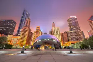 La escultura Cloud Gate Chicago en Millennium Park reflejando los rascacielos del centro y visitantes caminando alrededor