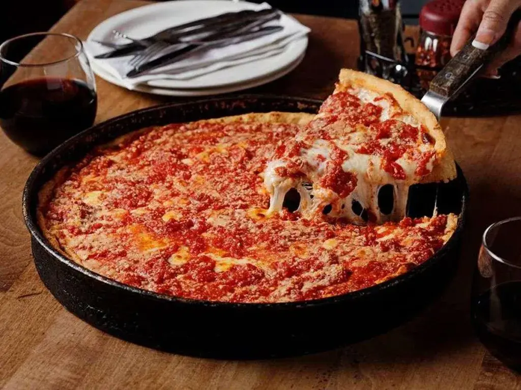 Pizza de Chicago estilo deep dish servida en un restaurante tradicional con el skyline de Chicago al fondo.