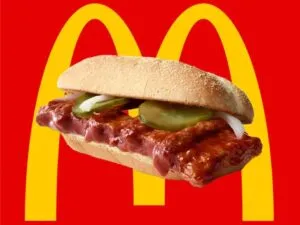 McRib en Chicago servido con salsa BBQ, cebolla y pepinillos sobre una mesa de restaurante.