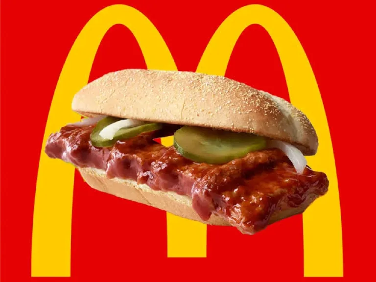 McRib en Chicago servido con salsa BBQ, cebolla y pepinillos sobre una mesa de restaurante.
