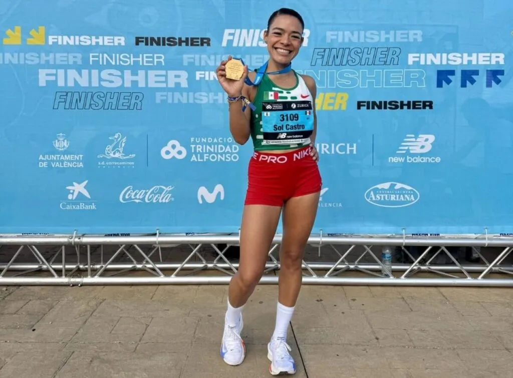 Atleta mexicana corriendo durante una competencia de atletismo con edificios de Chicago al fondo.