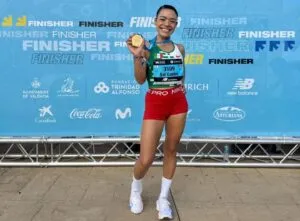 Atleta mexicana corriendo durante una competencia de atletismo con edificios de Chicago al fondo.