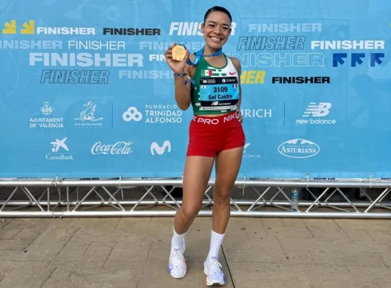 Atleta mexicana corriendo durante una competencia de atletismo con edificios de Chicago al fondo.